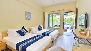 A hotel room with two beds, a TV, a dining table, and a view of the outdoors.