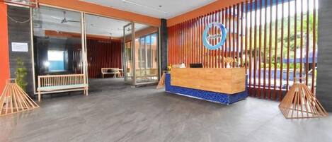 A reception area with a wooden reception desk, a glass partition, and a view of the outdoors.