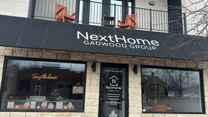Ein Gebäude mit einem Schild, auf dem "NextHome Gadwood Group" steht, und einem "Geschlossen“-Schild am Fenster.