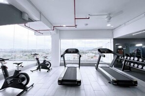 Ein Fitnessraum mit Laufbändern, Ergometer und einem Bereich für Krafttraining.
