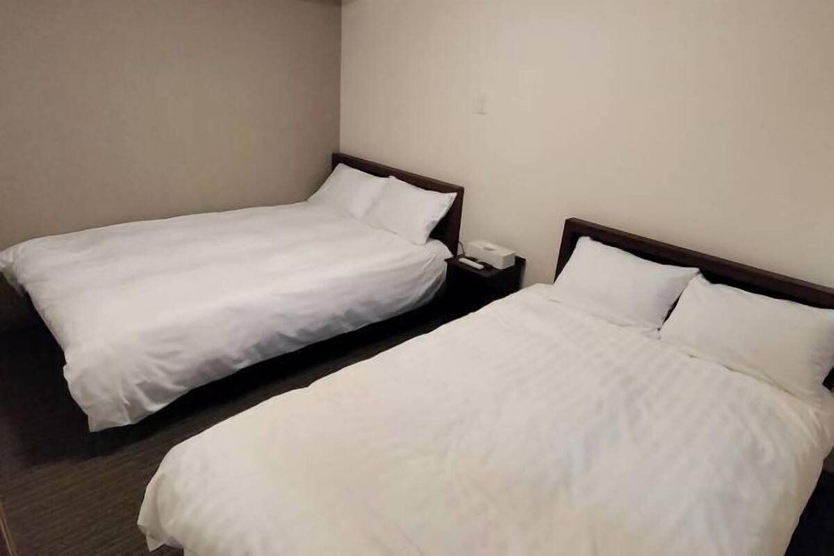 Two single beds with white bedding in a hotel room.
