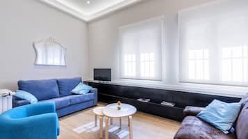 Een moderne woonkamer met een blauwe bank, een bruine bank en een kleine ronde tafel met een vaas.