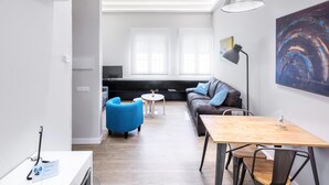 Una sala de estar moderna con un sofá, un sillón azul y una mesa de madera.