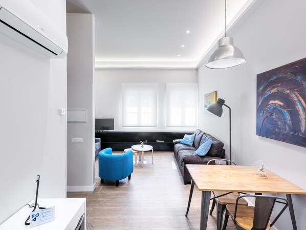 A modern living room with a sofa, blue armchair, and a wooden table. - Greco (Toledo)