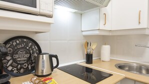 Ett modernt kök med en kaffebryggare, en vattenkokare, en skärbräda med kaffekapslar och en uppsättning träredskap.