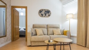 Ett vardagsrum med en soffa, ett litet runt bord, en lampa och en väggklocka.