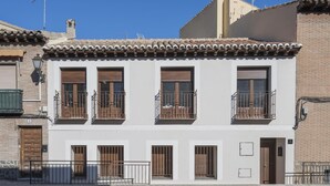 Un immeuble de deux étages avec une façade blanche, de nombreux balcons dotés de rampes en métal et un toit recouvert de tuiles.