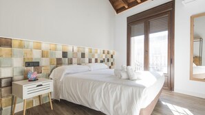 Une chambre avec un grand lit, une table de chevet, une tête de lit en bois et une vue sur l’extérieur grâce à une porte coulissante.