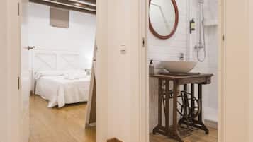 Hotellihuone, jossa on sänky, kylpyhuone, jossa on pesuallas ja peili, sekä puulattia.