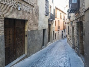 Une ruelle étroite pavée, bordée de bâtiments historiques aux façades en pierre et aux portes en bois.