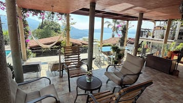 An outdoor patio with seating, a pool, and a view of the ocean.