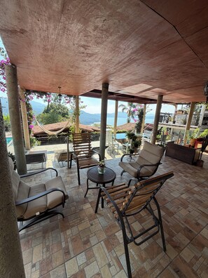 Une terrasse extérieure avec des sièges, une piscine et une vue sur l’océan.