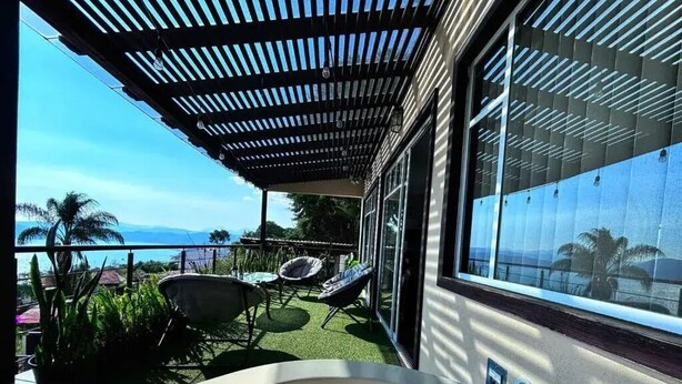 En balkon med jacuzzi, udendørs møbler og havudsigt.