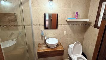 A bathroom with a glass-enclosed shower, a wooden vanity with a sink, and a toilet.
