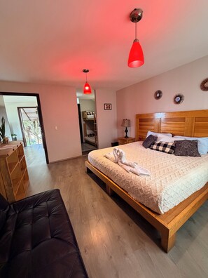 A bedroom with a wooden bed, a red pendant light, a bench, and a view of a balcony. - One-Bedroom Chalet (Valle de Bravo)