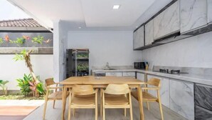 Een moderne keuken met marmeren aanrechtbladen, een houten eettafel en stoelen.