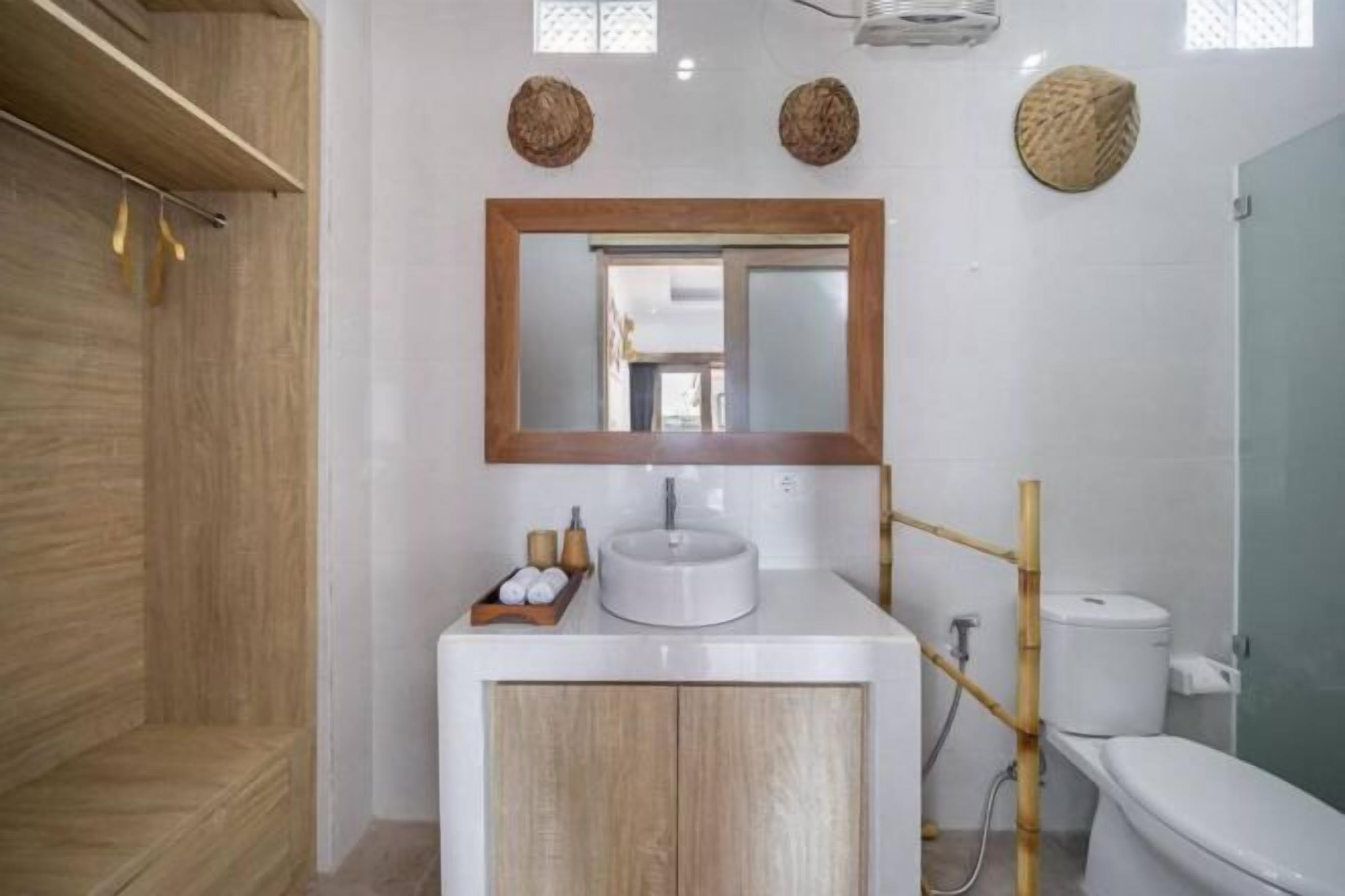 A modern bathroom with a wooden vanity, a round mirror, and a toilet.