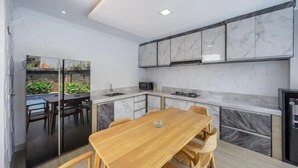 Een moderne keuken met marmeren kastjes, een houten eettafel en een zwarte koelkast.