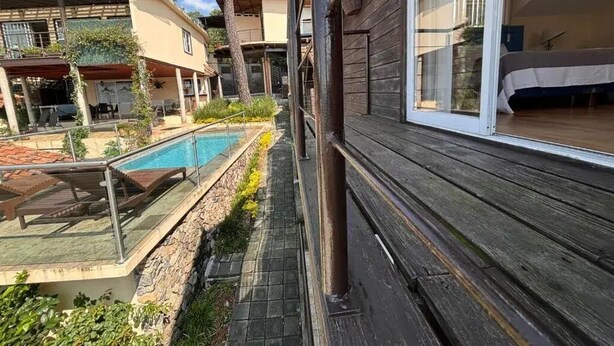 Een zwembadgedeelte met een houten terras, een glazen zwembad en een gebouw met grote ramen.