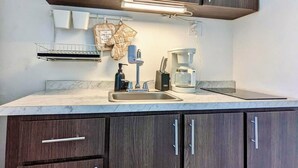 A modern kitchen with dark wood cabinets, a marble countertop, and basic appliances. - Stylish Ocean view w/ HotTub BBQ (Arecibo)
