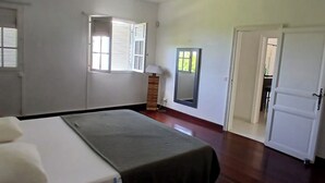 A room with a bed, a window with shutters, a mirror, and a door leading to another room. - Villa TERRAVIVA- Saint François  8 pers.- 4 ch- 3 sbb, piscine, WiFi, AC (Saint-François)
