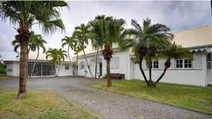 A white building with a gravel driveway and palm trees. - Villa TERRAVIVA- Saint François  8 pers.- 4 ch- 3 sbb, piscine, WiFi, AC (Saint-François)