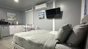 A modern bedroom with a bed, bedside table, and a potted plant.