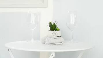 Een witte tafel met twee lege wijnglazen en een kleine potplant met een opgerolde handdoek erop.