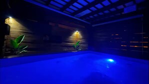 An indoor swimming pool with a wooden wall and a sloped ceiling.