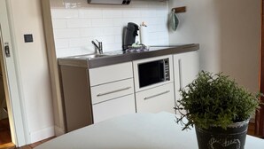 Una cocina moderna con armarios blancos, encimera negra y una planta en la mesa.