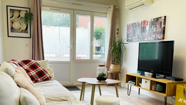 A living room with a sofa, a TV, a small table, and a window with curtains. - Apartment Lumières (Pontault-Combault)