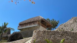 A stone building with a thatched roof balcony. - Umarato Villa Sumba (Wanokaka)
