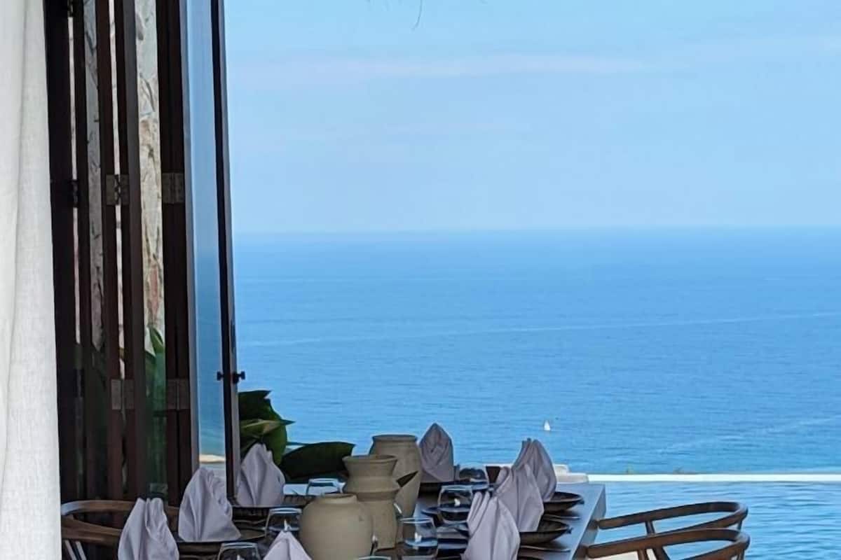 A table set for dining with a view of the ocean.