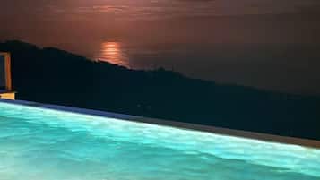 A swimming pool with a view of the ocean at night.