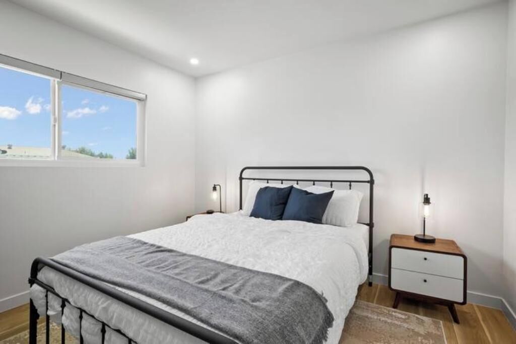 Une chambre à coucher avec un lit, des tables de chevet, une fenêtre et une vue sur l’extérieur.