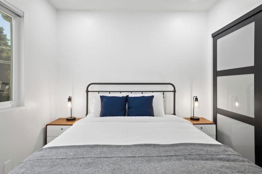 A modern bedroom with a bed, two bedside tables, and a window.