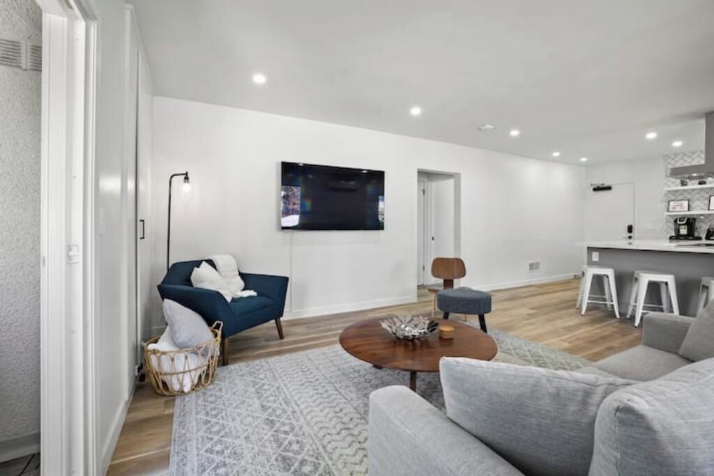 A modern living room with a grey sofa, a blue armchair, and a wooden coffee table.