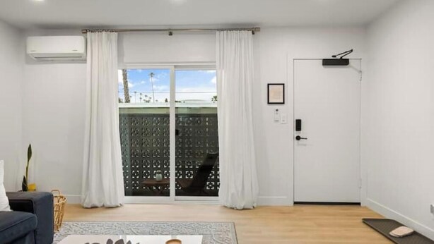 Un salon moderne avec un canapé, une table basse et une porte-fenêtre coulissante donnant sur un balcon.