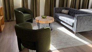 A modern living room with a grey sofa, two green armchairs, and a round wooden coffee table. - Boutique hotel near street car and convention center (Tucson)