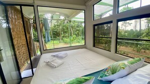 A room with a bed, large windows, and a view of greenery. - Jungle Bus, 5 min drive PlayaLinda, 15 x Dominical, Wifi Starlink (Savegre de Aguirre)