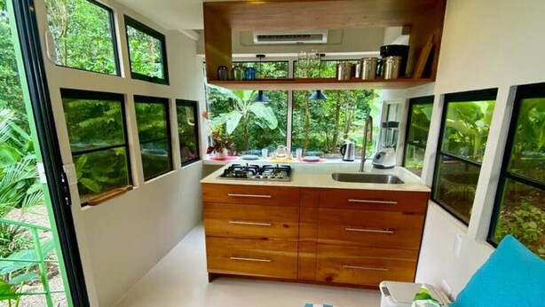 A compact bedroom with a bed, a small kitchenette, and large windows. - Jungle Bus, 5 min drive PlayaLinda, 15 x Dominical, Wifi Starlink (Savegre de Aguirre)