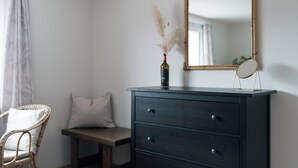 A room with a dark wooden dresser, a mirror, a bottle of wine, and a wicker chair. - Epic view and sun sets from spacious 4 bedroom apartment. Large families +groups (Amden)