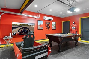 A room with a red wall, a pool table, a racing simulator, and a mannequin dressed in racing gear. - La Ferrari - Old Town Scottsdale - Heated Pool (Scottsdale)
