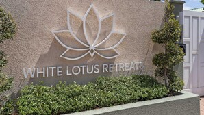 Letrero de White Lotus Retreats con logotipo de flor de loto y texto.
