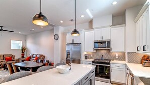 Una cocina moderna con armarios blancos, electrodomésticos de acero inoxidable e iluminación colgante.