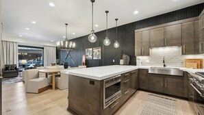 Een moderne keuken met een groot eiland, donkerhouten kastjes en hanglampen.