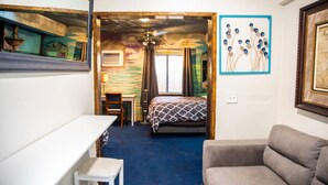 Een kleine hotelkamer met een bed, een bureau, een stoel en een bank.