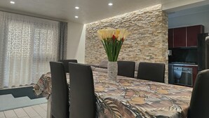 Et moderne spiseområde med et mønstret borddække, en vase med blomster og en væg med stenudsmykning.