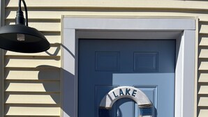 Una puerta azul con un letrero circular que dice "LAKE HOUSE" y un timbre.