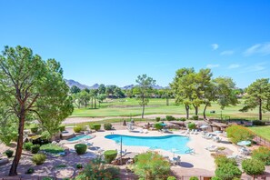 A resort with a swimming pool, lounge chairs, and a golf course in the background. - CASA RANCHERO: Cowboy up, golf course view. (Phoenix, Arizona)